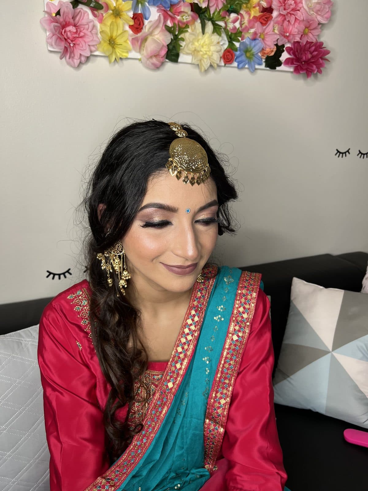 Party makeup client in a red and teal outfit with floral backdrop by 902 Beauty Bar, Dartmouth NS